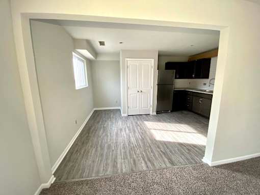 A room with a white door leading to a kitchen.