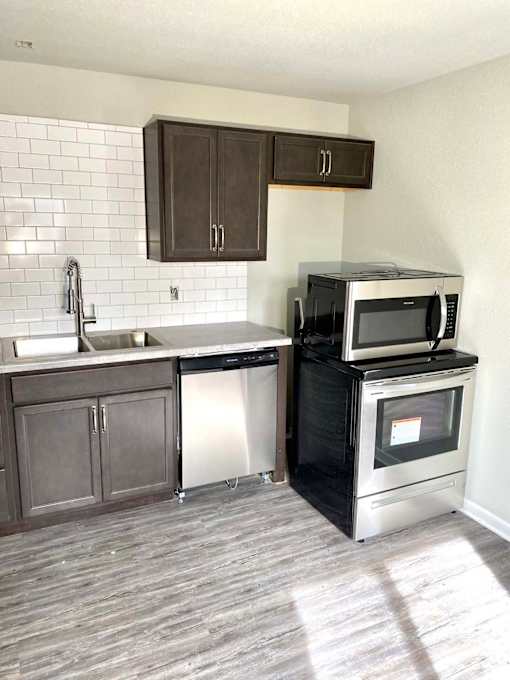 A kitchen with a black microwave oven on a black cabinet.