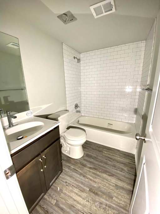A white tiled bathroom with a wooden floor.