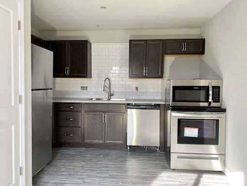 A kitchen with dark brown cabinets and a white tiled backsplash.