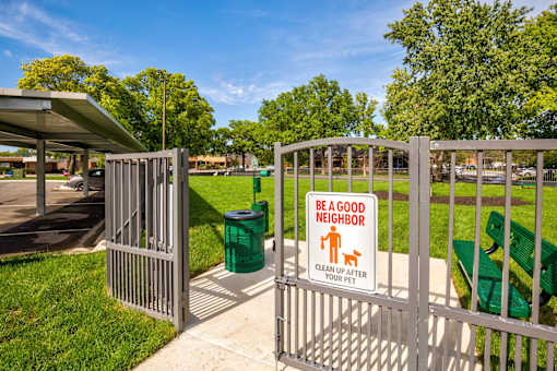 A sign on a gate reads "Be a good neighbor clean up after your pet".