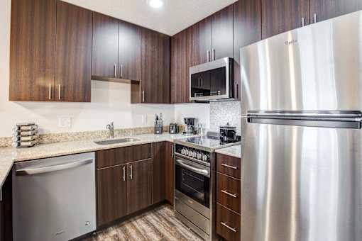 A modern kitchen with a stainless steel refrigerator, microwave, and oven.