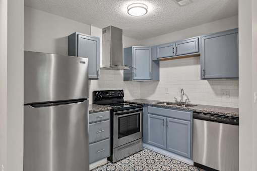 A kitchen with a stainless steel refrigerator, oven, and sink.