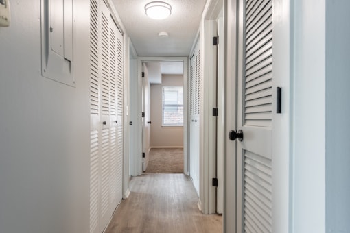 a hallway with white shutters and a light on the ceiling