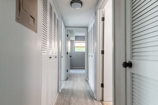 a long white hallway with white shutters on the sides of the door
