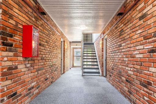 a long corridor with brick walls and a staircase in the middle