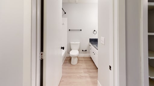 a renovated bathroom with white walls and wood floors