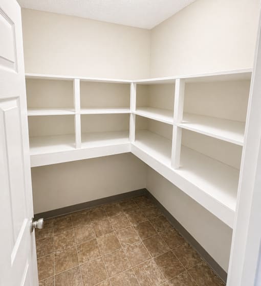 Empty white shelves in a room with brown tiled flooring.