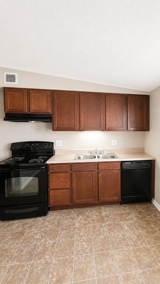 A kitchen with a black stove top oven and black dishwasher.