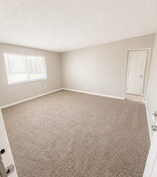 A room with a carpeted floor and a door on the right side.