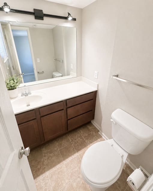 A white toilet sits in a bathroom next to a sink and a mirror.