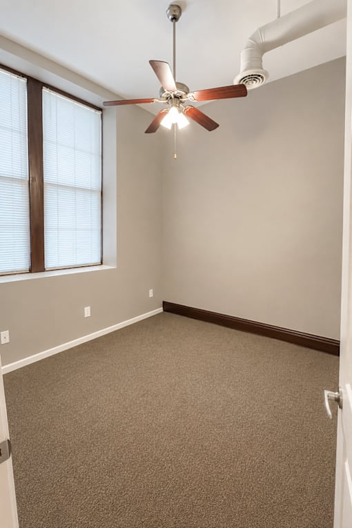 A room with a ceiling fan and a window with blinds.