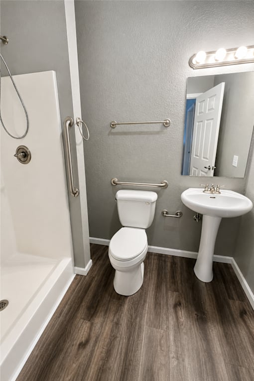 A white toilet sits in a bathroom next to a sink and a bathtub.