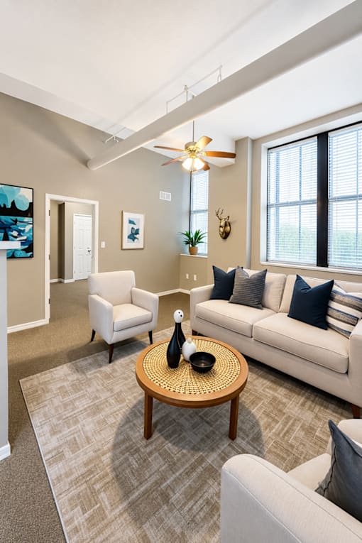 A living room with a white couch, a wooden coffee table, and a ceiling fan.