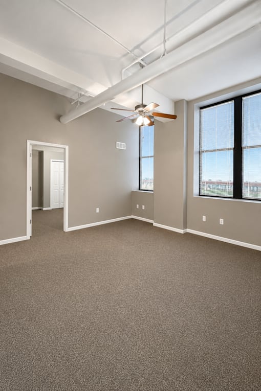A room with a ceiling fan and a window overlooking a cityscape.