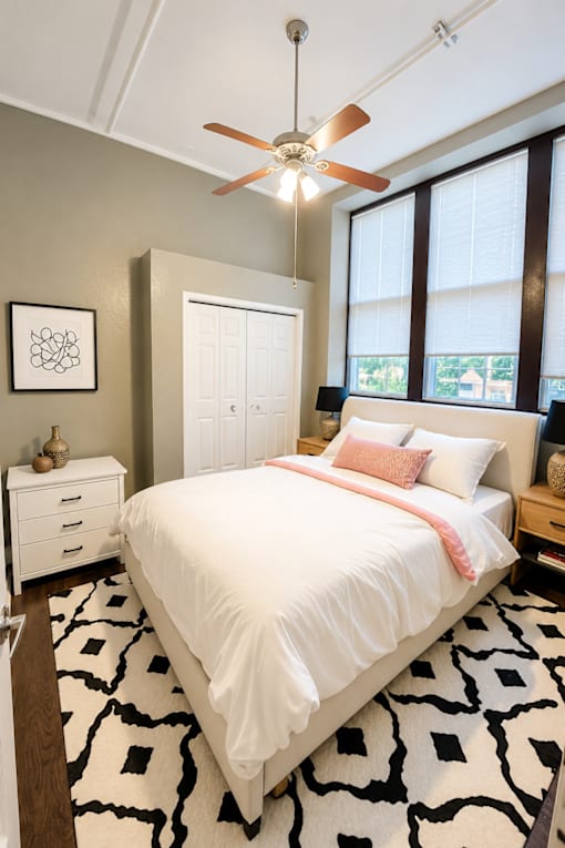 A bedroom with a white bed and a black and white rug.