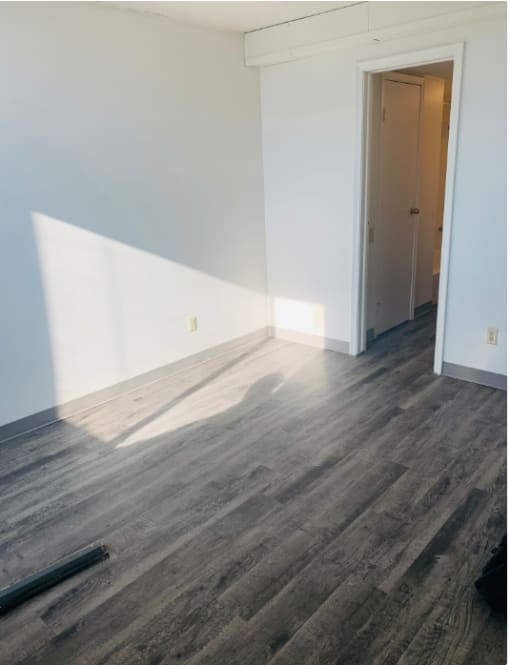 an empty room with white walls and wood floors