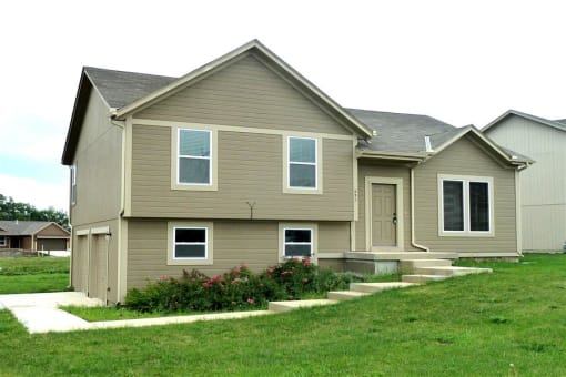 a tan house with a lawn and a sidewalk
