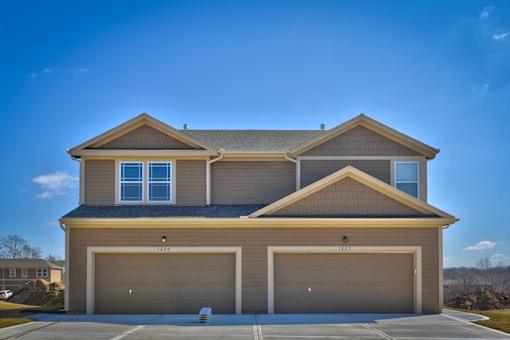 a tan house with two garage doors