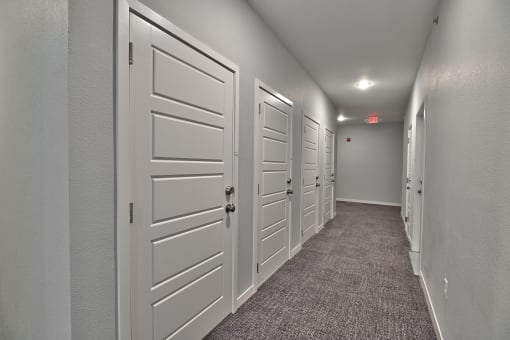 a hallway with white doors and carpeted floors
