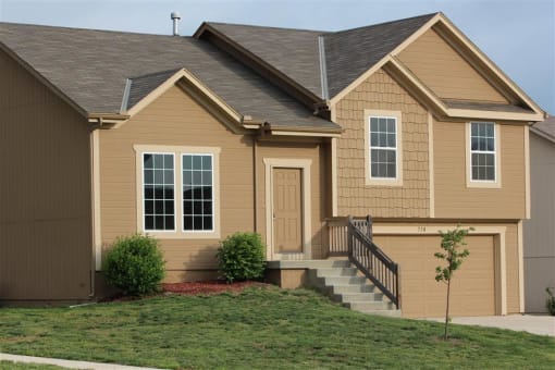 a brown house with a front porch and a yard