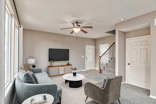 a living room with couches and a ceiling fan