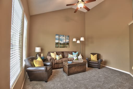 a living room with couches and chairs and a ceiling fan