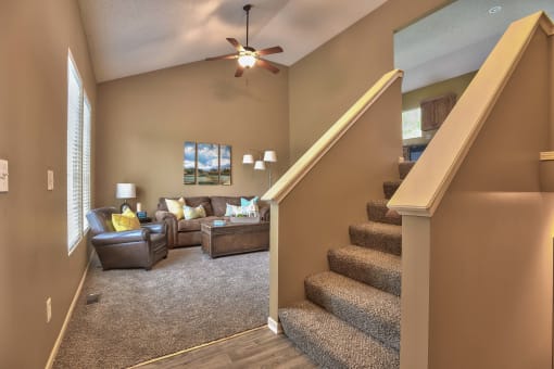 a living room with stairs and a ceiling fan