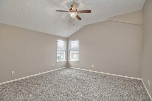 an empty living room with a ceiling fan and a window