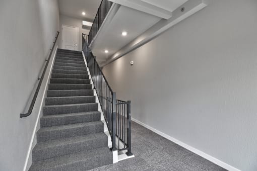 a staircase in a house with grey carpeted stairs and a white door