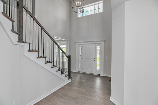 A white interior with a staircase and a chandelier.
