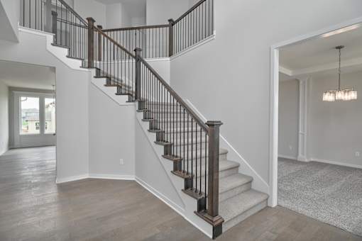 A staircase with a wooden handrail and a light fixture above it.