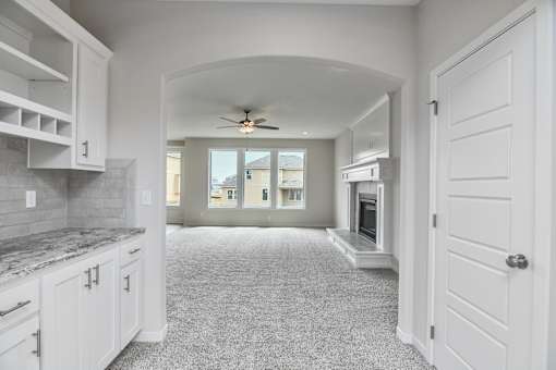 A spacious kitchen with white cabinets and a marble countertop.