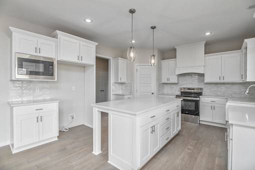 A modern kitchen with white cabinets and a wooden floor.
