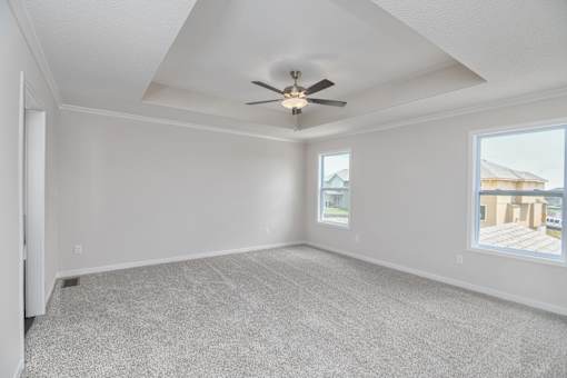 A spacious room with a ceiling fan and carpeted floor.