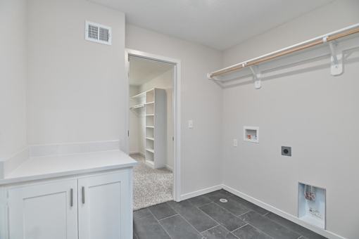 A white kitchen with a cabinet and a small white fridge.