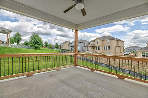 A patio with a black railing and a ceiling fan.