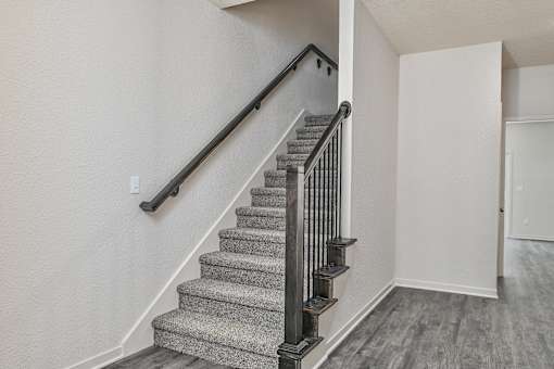 A staircase with a metal railing and a carpeted runner.