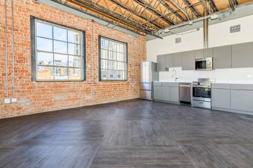 A large empty room with a brick wall and wooden flooring.