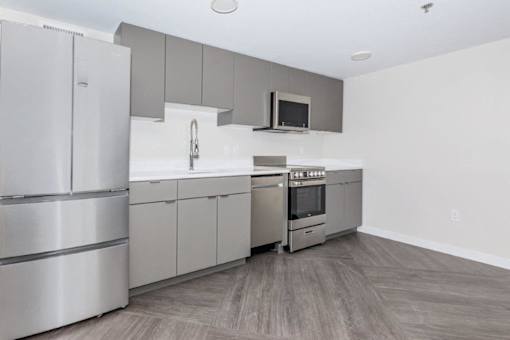 A modern kitchen with stainless steel appliances and wooden flooring.