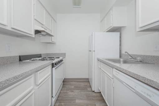 A white kitchen with a stove, oven, and refrigerator.