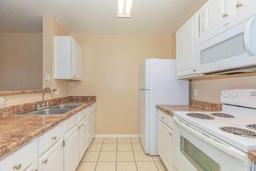 A kitchen with white appliances and granite countertops.