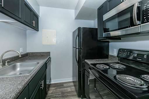 A black refrigerator and microwave in a kitchen.