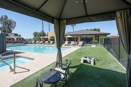 a backyard with a pool and a patio with chairs and a table