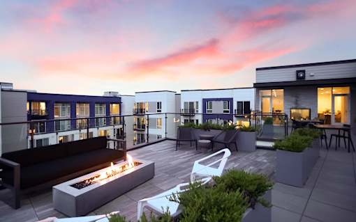 A modern outdoor seating area with a fire pit and chairs.