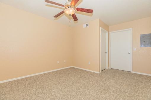 A room with a ceiling fan and carpeted floor.