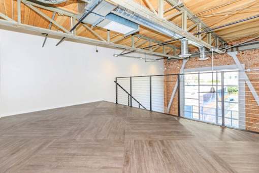 A room with wooden floors and a brick wall with a window.