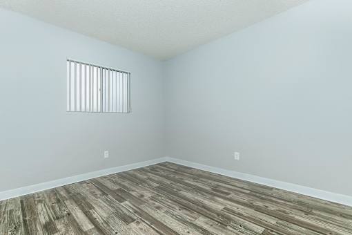 A room with a window and wooden flooring.