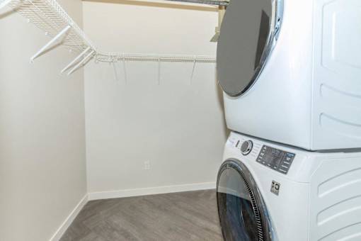 A white dryer is in a laundry room with a white wall and a white hanger.