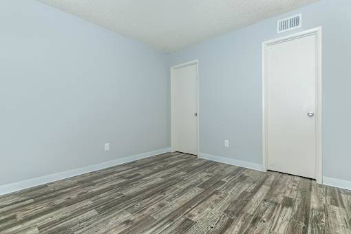 A room with a wooden floor and two doors.